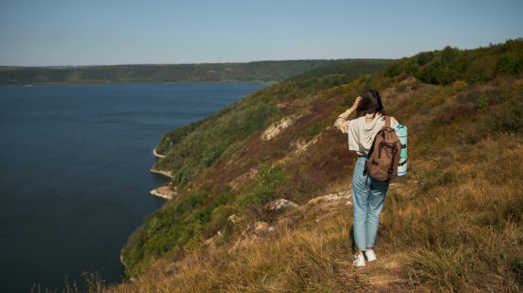 Eine junge Dame mit Rucksack beim Wandern am Plansee, umgeben von kristallklarem Wasser und beeindruckender Berglandschaft.